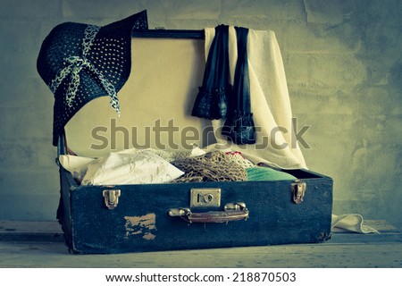 Open suitcase with old things on the brick wall background