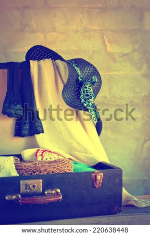 Open suitcase with old things on the brick wall background
