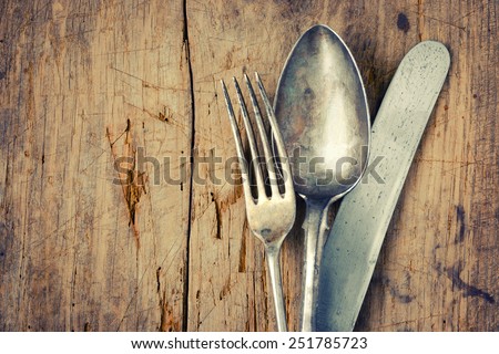 Fork, spoon and knife close up on an old wooden board