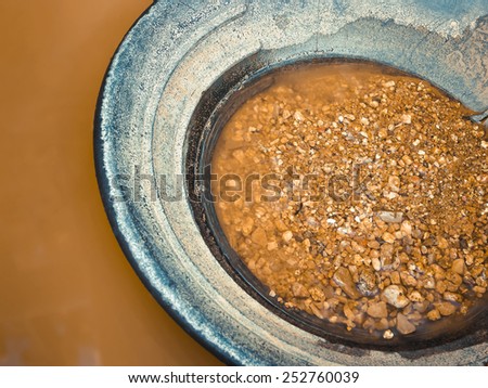 Pan with gold sand and river water