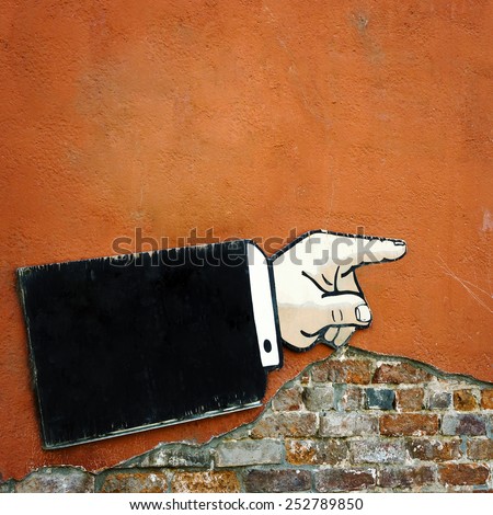 Pointer to the direction of motion in the form of hands hanging on an old brick wall