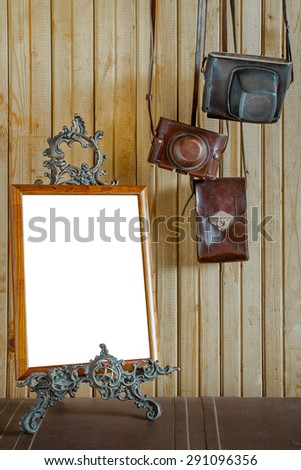 Old cameras and wooden frame for a photo on a bronze pedestal