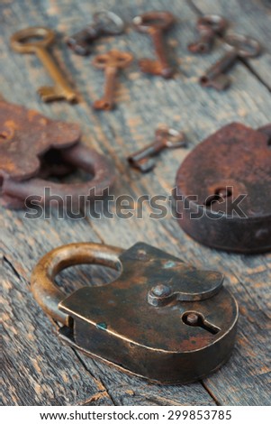 Old padlocks with keys lie on a wooden board