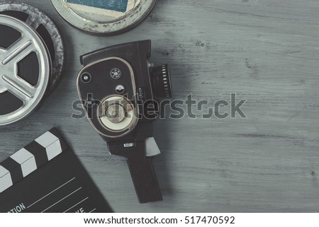 Old movie camera with film reels and a clapper board lying on the painted table