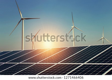 solar panel and wind turbine with sunrise background. concept clean energy