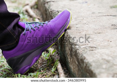 The purple sneakers on the cement.