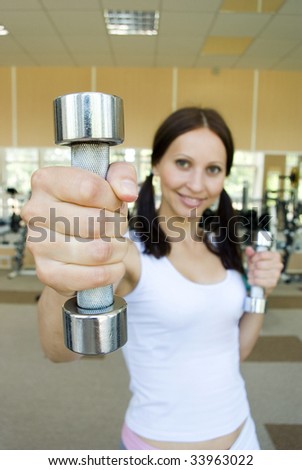 A woman in gym clothes, holding weights.