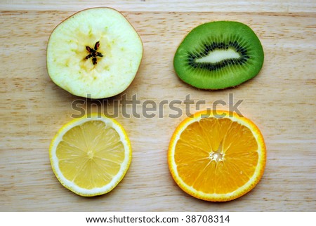 Slices of fruits : kiwi, orange, apple, lemon on wooden background