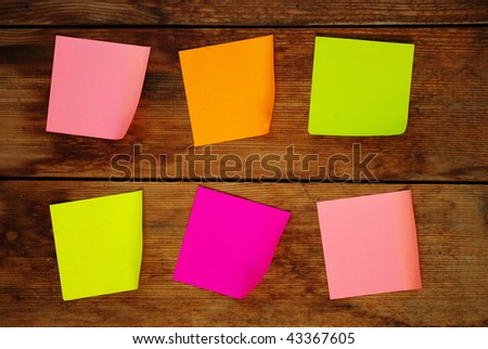 Five colored empty sticker notes on wooden surface
