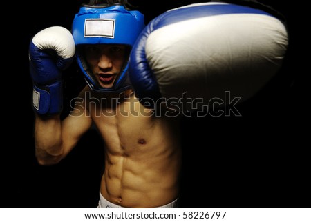 Portrait of young man with boxing helmet and gloves over black background