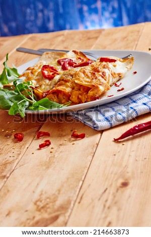 Enchiladas dish with chili peppers and on a wooden table, with space