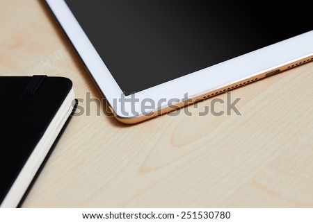 White digital tablet cropped sitting on a wooden desk, detail shot