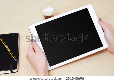Hands touching on a white digital tablet, on a wooden desk and a coffee