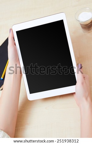 Girl watching on a digital tablet blank screen, on a wooden desk