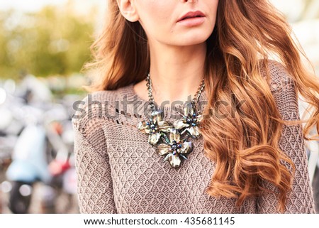 Close up view of a girl with long hair wearing a grey sweater and a necklace