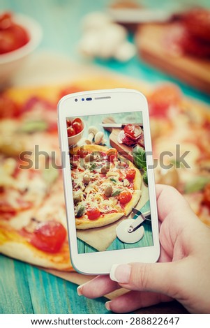 Woman taking a photo of Pizza and Ingredients with smartphone
