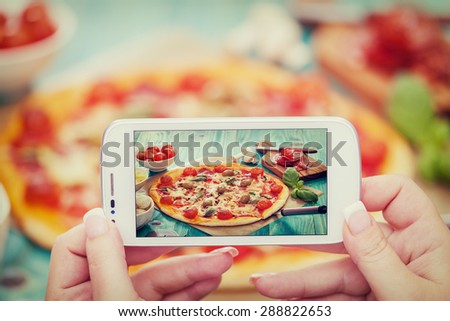 Woman taking a photo of Pizza and Ingredients with smartphone