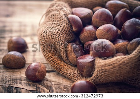 fresh chestnuts in jute sack on the old wooden background