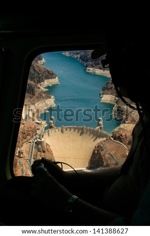 Aerial shot of the Hoover Dam, Arizona. Famous American landmark as seen from a tour vehicle window with a tourist silhouette looking at it.