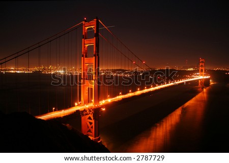golden gate bridge seen at night showing some fog and the city lights