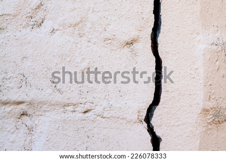 A large crack developed in a painted brick wall. This caused by a big tree root gradually lifting the wall. Cemented joins in the bricks are clearly visible./Wall Crack/Brick Wall Crack