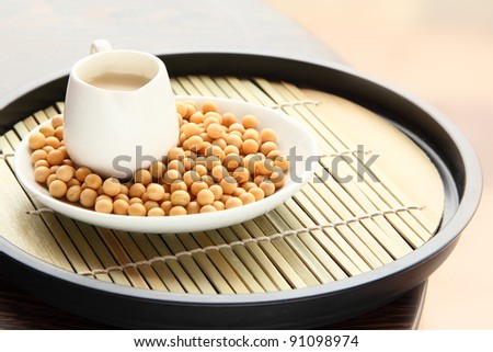 Soy bean milk jar with raw soy beans on traditional bamboo mat