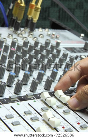 A generic music mixer in studio with a finger adjusting the slider/fader