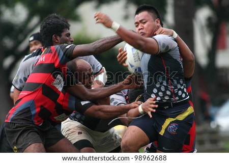 KUALA LUMPUR-MARCH 31: Three SAHOCA players try to tackle an UiTM Lions player during a Malaysian Rugby Union Super League 2012 match (UiTM Lions vs SAHOCA) on March 31,2012 in Kuala Lumpur,Malaysia