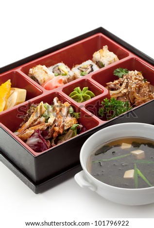 Japanese Meal in a Box (Bento) - Salad, Meat Cuts and Sushi Roll, Orange and Banana. Garnished with Miso Soup