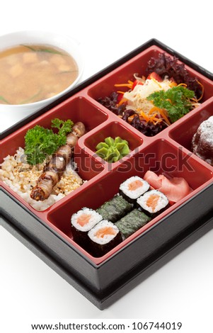 Japanese Meal in a Box (Bento) - Salad, Skewered Meat with Rice, Salmon Sushi Roll and Dessert. Garnished with Miso Soup