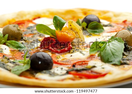 Pizza with Mozzarella Cheese and Fresh Tomato and Pesto Sauce. Garnished with Dried Tomato, Green and Black Olives and Basil Leaves
