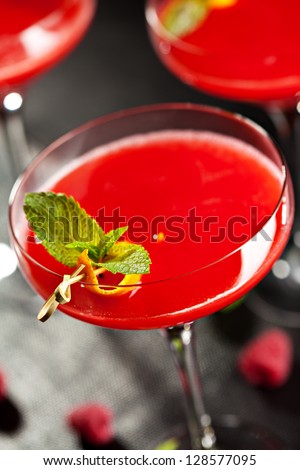Red Alcoholic Cocktail with Raspberry Gin. Garnished with Fresh Mint Leaves and Lemon Citron