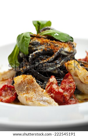 Black Spaghetti with Sea Bass and Batarga and Dried Cherry Tomato. Served with Fresh Corn Salad Leaves