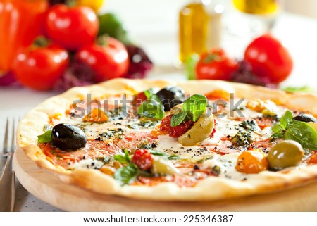 Pizza with Mozzarella Cheese, Fresh Tomato and Pesto Sauce. Served at Restaurant Table