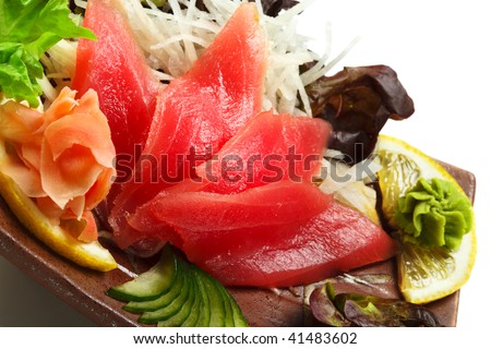 Tuna Sashimi - Maguro (fresh raw tuna) on Daikon (White Radish). Garnished with Ginger, Wasabi, Seaweed, Cucumber, Salad Leaf and Lemon