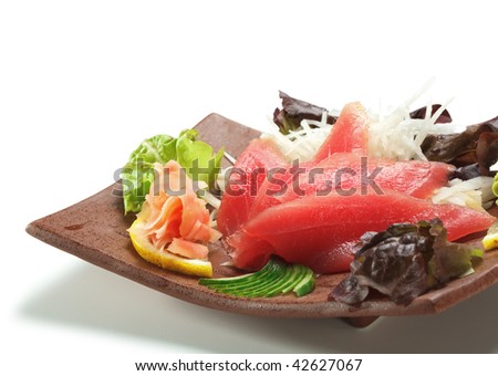 Tuna Sashimi - Maguro (fresh raw tuna) on Daikon (White Radish). Garnished with Ginger, Wasabi, Seaweed, Cucumber, Salad Leaf and Lemon