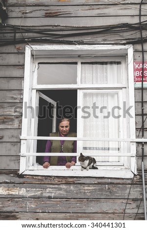 Istanbul, Turkey - November 14, 2015: Unidentified lady posing for visitors with her cat sitting by the window in the historical neighborhood of Balat, Istanbul on November 14.