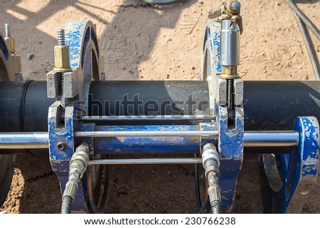the mechanic works at a welding machine for connection of plastic pipes
