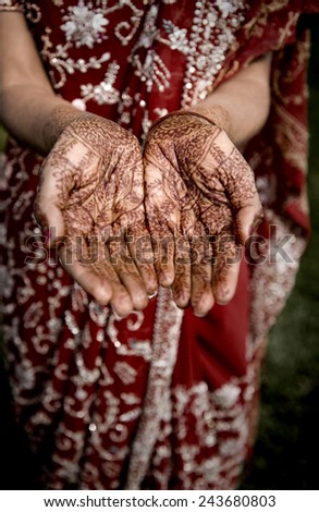 An Indian bride shows off her traditional Mehndi Henna hand tattoos at a Hindu wedding.  Selective focus blurs the rest of the background.