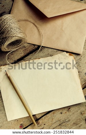 Old white sheet of paper and a pencil on a wooden background.The envelope and the coil of twine.