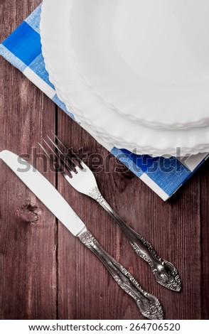 Brown Desk with a set of white plates and a knife with a fork.