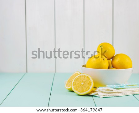 Fresh lemons in a white bowl on wooden background.Half of lemon.