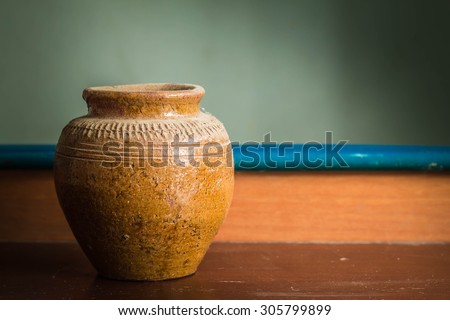 Old jar that sits on a wooden table.