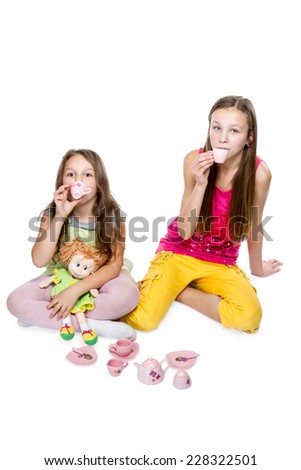 Two girls play tea party baby dishes isolated on white background