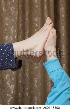 Legs mother feet touch the kid feet dressed in pajamas on a background of curtains