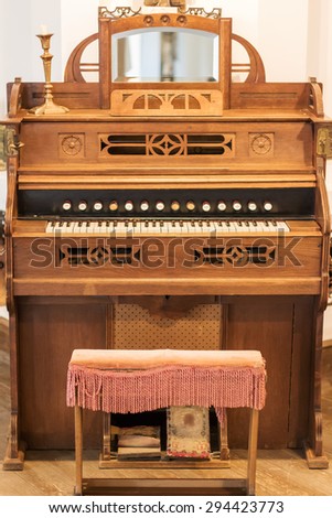 Vintage brown American musical organ closeup with a chair
