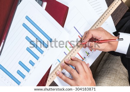Hands of businessman draw a line on the chart with a ruler and pencil