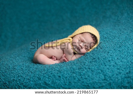 Baby curled on on teal blanket with feet crossed