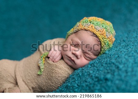 Close up of newborn sleeping in a green and yellow knit hat