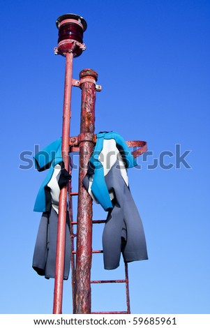 Wet diving suit hanging on a iron pile to dry